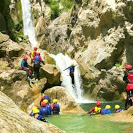 Un participante de barranquismo para principiantes con traslado desde Split, organizado por Adventure Dalmatia, está parado debajo de una cascada en el cañón.