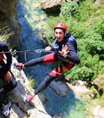 Een deelnemer aan de Extreme Canyoning met Stadstransfer vanuit Split bij de Cetina rivier maakt zich klaar om over een klif naar beneden te touwen met de hulp van een ervaren gids van Adventure Dalmatia.