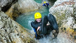 Eine junge Frau rutscht beim Canyoning in der Sušec-Schlucht mit A2 Rafting Kobarid eine der natürlichen Wasserrutschen hinunter.