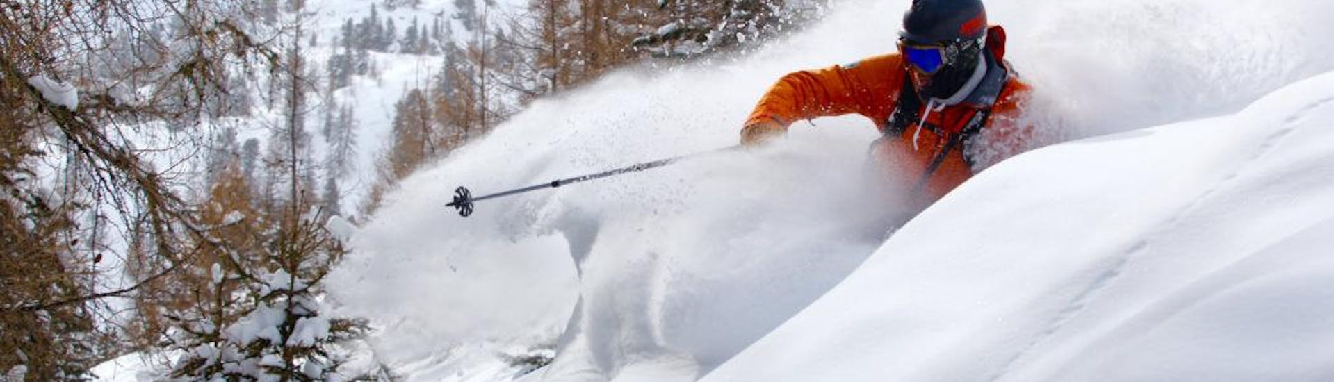 Ein Skifahrer fährt die Hänge hinunter, während er mit der Skischule Zenit private Freeride Touren für alle Levels unternimmt.