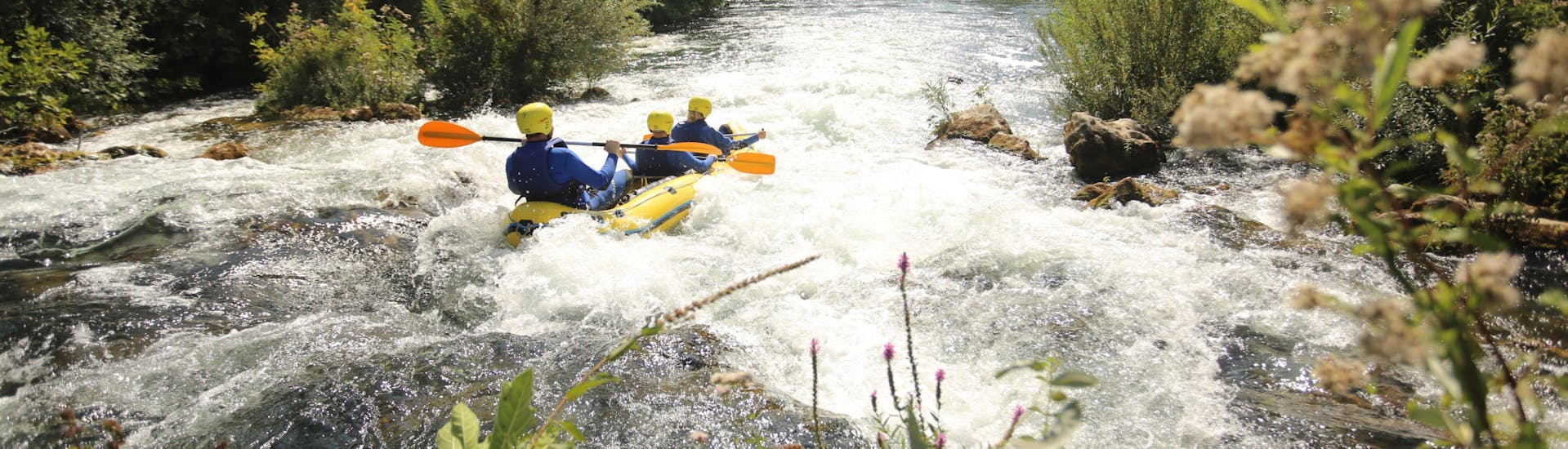 Een groep mensen peddelt over een van de onstuimige stroomversnellingen tijdens het raften op de Cetina-rivier met Active 365.