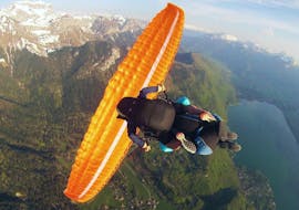 Ein Mann genießt sein Tandem-Gleitschirmflug über dem Annecy-See, eine Sensations-Aktivität mit Flyeo.