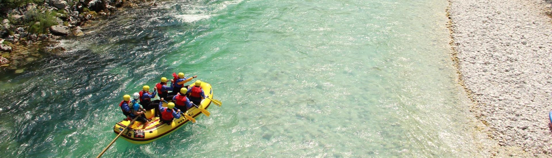 Eine Gruppen an Teilnehmern fahren auf einer ruhigen Passage beim Wildwasser-Rafting im Soča-Tal - Standard-Tour mit TOP Rafting Centre.