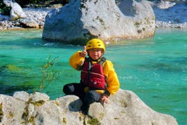 Een jongen zit op een rots na de familie Rafting Tour op de Soča rivier in Kobarid met Soča Flow Kobarid.