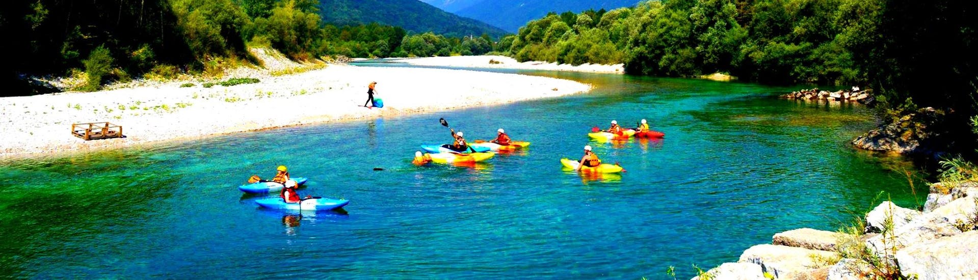 Ein Bild von einigen Teilnehmern in Kajaks während der Kajaktour auf dem Fluss Soča in Kobarid mit Soča Flow Kobarid.