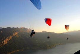 During Tandem Paragliding "The Classic" in Interlaken, three paragliders of Twin Paragliding are flying into the sunset over Lake Thun.