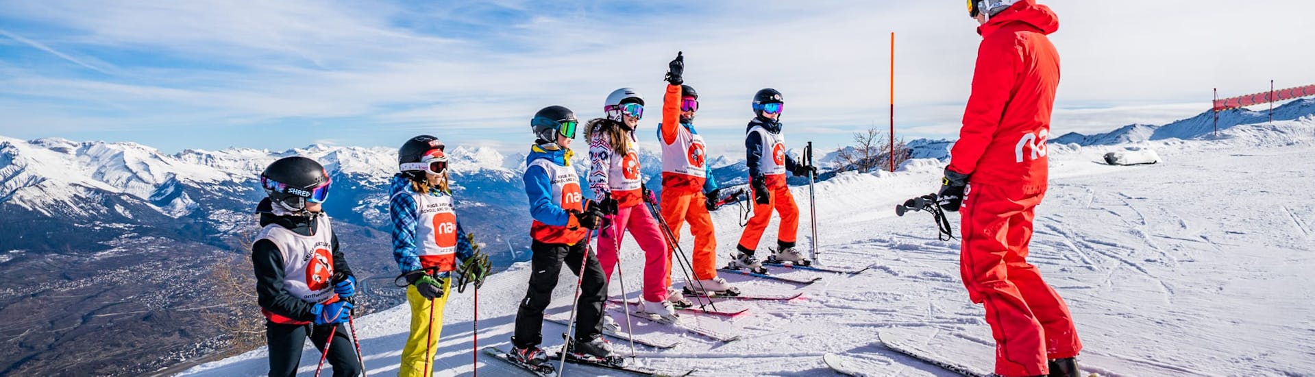 Image d'un moniteur Neige Aventure enseignant le ski à un groupe de jeunes enfants.