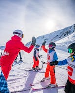 Bild eines Neige Aventure Skilehrers, der einem Kind seiner Gruppe während eines Gruppenskikurses von Neige Aventure ein High-Five gibt.