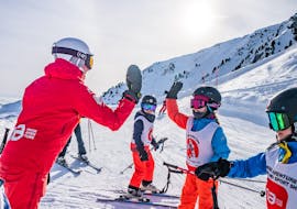 Image d'un moniteur félicitant l'un des enfants de son groupe pendant une leçon de ski de Neige Aventure.
