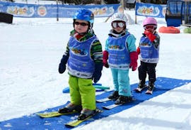 Drie kinderen oefenen in de kleuterschool tijdens de kinderskilessen "Bolgen" (4-7 jaar) voor beginners met de Zwitserse skischool van Davos.
