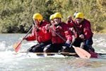 Während des Floßbau Team Event (ab 8 Personen) auf der Loisach mit Montevia paddelt eine Gruppe von Kollegen mit ihrem selbstgebauten Floß den Fluss entlang.