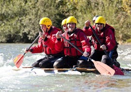 During the Raft Building Team Event (8+ ppl.) on the Loisach river with Montevia, a group of colleagues is paddling along the river on their self-made raft.