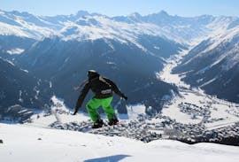 Un snowboarder fait un saut pendant les cours de snowboard pour enfants (6-13 ans) pour débutants avec l'école de ski suisse de Davos.