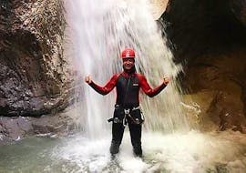 A woman standing underneath a waterfall during Rafting & Canyoning on the Kitzbüheler Ache with Der Guide Brixental.