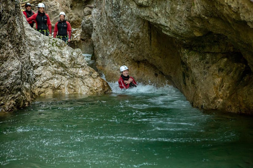 Eine Frau rutscht beim Canyoning in der Strubklamm - Ganztagestour mit Der Guide Brixental in die Fluten der Schlucht hinunter.