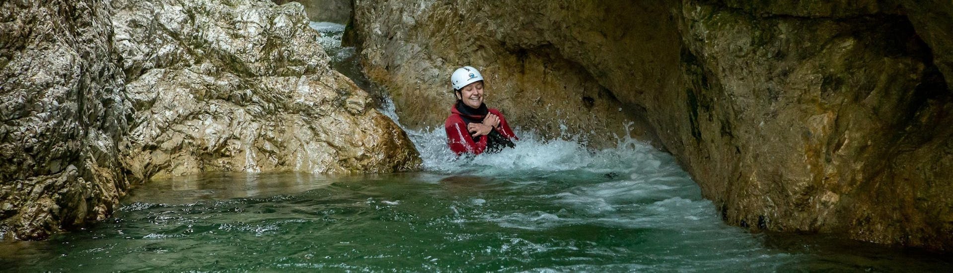 Een vrouw glijdt naar beneden in het water van de canyon tijdens Canyoning in Strubklamm - Hele dag tour met Der Guide Brixental.