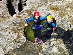 2 kinderen liggen in een natuurlijke waterpoel tijdens hun canoyingtocht in Almbach met Torrent Outdoor Experience.