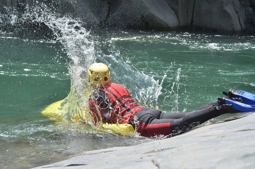 A young man is entering the water and is about to start the Hydrospeed on the Sesia River - Gorge Tour with Eddyline - The River Experience Valsesia.