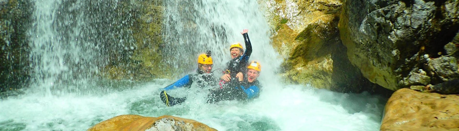 Drei Freunde genießen ein erfrischendes Bad unter einem Wasserfall, nachdem sie die anspruchsvollen Abseilpassagen des Ultimate Canyoning im Altersbach mit Torrent Outdoor Experience gemeistert haben.