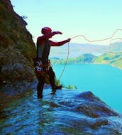 A guide from Torrent Outdoor Experience is preparing an abseiling passage during the Ultimate Canyoning in the Altersbach with a view of the Mondsee.