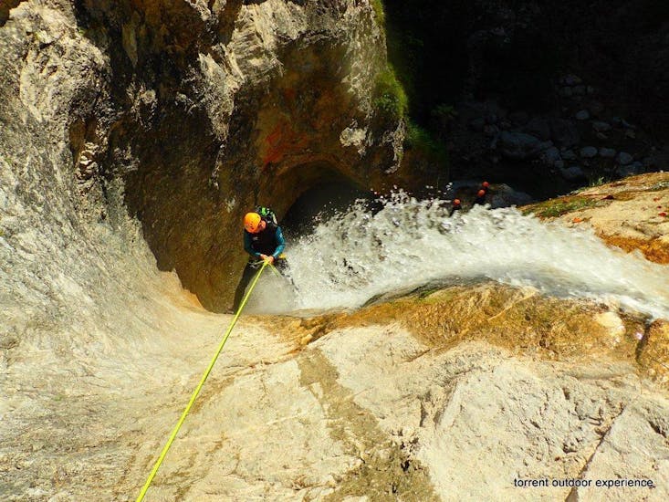 Ein Mann, der sich bei seiner Canoying "Vertikale" Tour mit Torrent Outdoor Experience in Fischbach an einem Wasserfall abseilt.