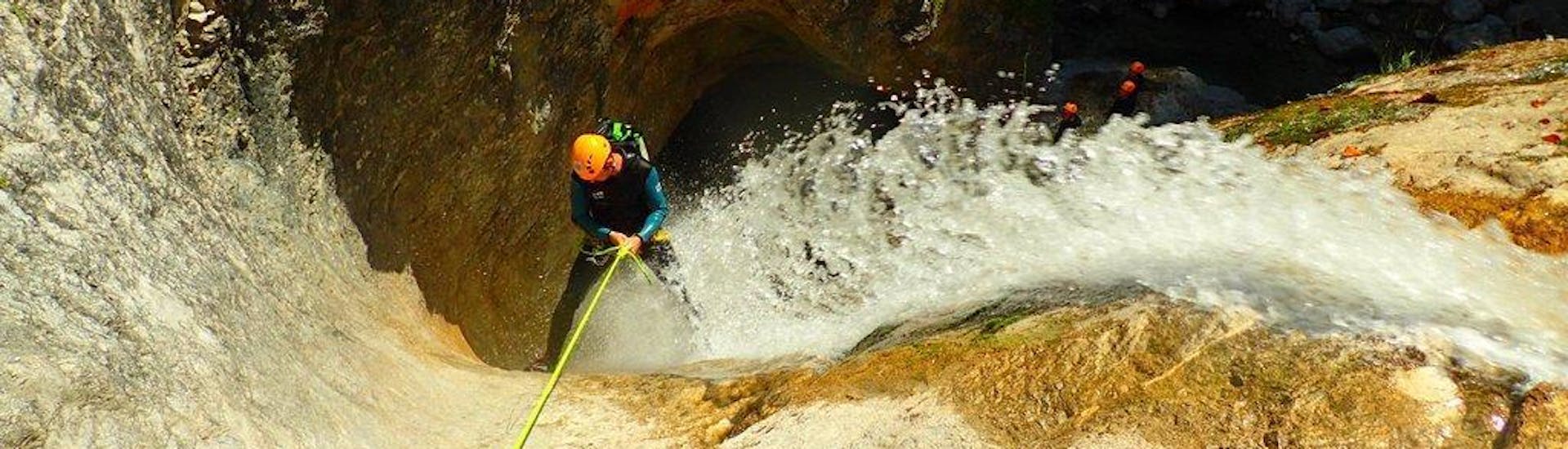 Ein Mann, der sich bei seiner Canoying "Vertikale" Tour mit Torrent Outdoor Experience in Fischbach an einem Wasserfall abseilt.
