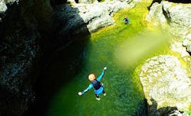 A woman jumping down the canyon into the fresh mountain water as part of her canyoning day trip to Fischbach and Almbachklamm with Torrent Outdoor Experience.