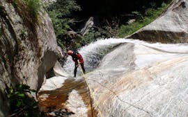 Un uomo attraversa una cascata durante la sua scalata nel Canyoning nella Sorba con Eddyline - The River Experience Valsesia.Ci incontriamo alla nostra base all'ora prenotata.