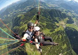 Ein Pilot und eine Kundin gleiten durch die Luft während des Tandem Paragliding vom Bischling in Werfenweng - Panorama mit Flugschule Austriafly Werfenweng.