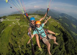 Een gids en een deelnemer maken een foto tijdens tandem paragliding in de stad Salzburg met FlyTandem Salzburg.
