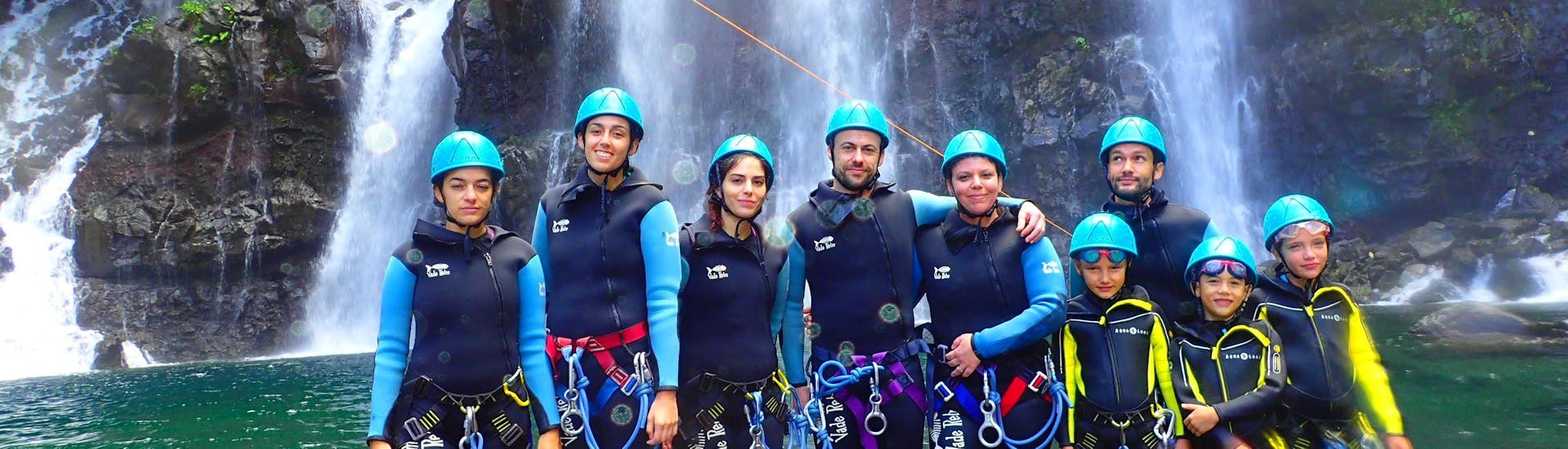 Participants on the River Trekking & ZipLine in Canyon du Langevin tour on Reunion Island with Cilaos Aventure are taking a picture in front of a waterfall.