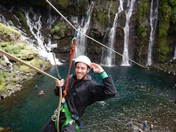Un homme se prépare à une descente en tyrolienne dans un lac au pied d'une cascade pendant sa sortie Aqua Rando & Tyrolienne dans le canyon du Langevin sur l'île de la Réunion avec Cilaos Aventure.