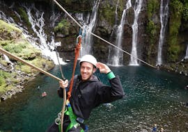A man is preparing himself for a zip line descent into a lake at the foot of a waterfall during his River Trekking & ZipLine outing in Canyon du Langevin on Reunion Island with Cilaos Aventure. 