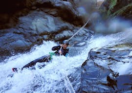 A woman is sliding down a natural slide during a Canyoning in Half Bras Rouge Canyon - Aquatic tour with Cilaos Aventure.
