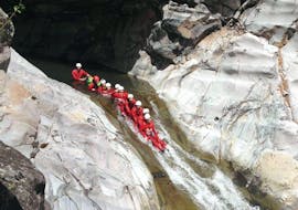 Participants of the canyoning trip "Aqualand" - Trou Blanc with Cilaos Aventure are sliding down a natural slide one behind the other.
