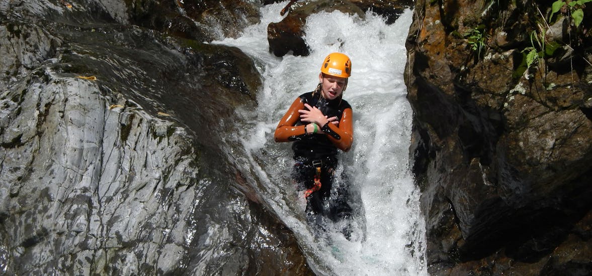 A person sliding down a waterfall while fun canyoning near Lake Weissensee in Carinthia with ARES Drautal Canyoning