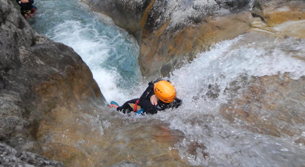 A person sliding down a waterfall while action canyoning near Lake Weissensee in Carinthia with ARES Drautal Canyoning.