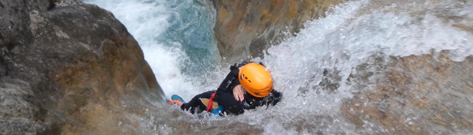 A person sliding down a waterfall while action canyoning near Lake Weissensee in Carinthia with ARES Drautal Canyoning.