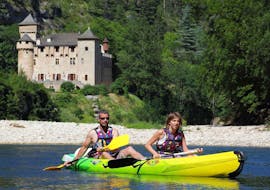 A couple is paddling in front of one of the castles that can be seen during the 21km Canoe Tour in Gorges du Tarn with Le Soulio.