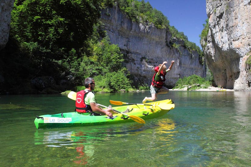 A child is jumping in the limpid waters of the Tarn during the 21km Canoe Tour in Gorges du Tarn with Le Soulio.