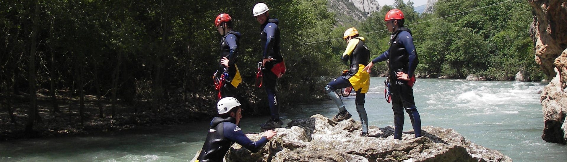 Beginner canyoners are standing on a rock in the river after finishing their canyoning tour in the Barranco de Sant Pere with La Rafting Company.