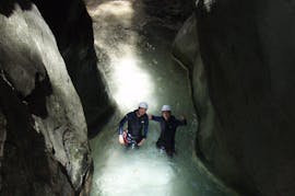 A couple stands in an underground river in the Barranco de Sant Pere and smiles into the camera during the Canyoning Beginner Tour with La Rafting Company.