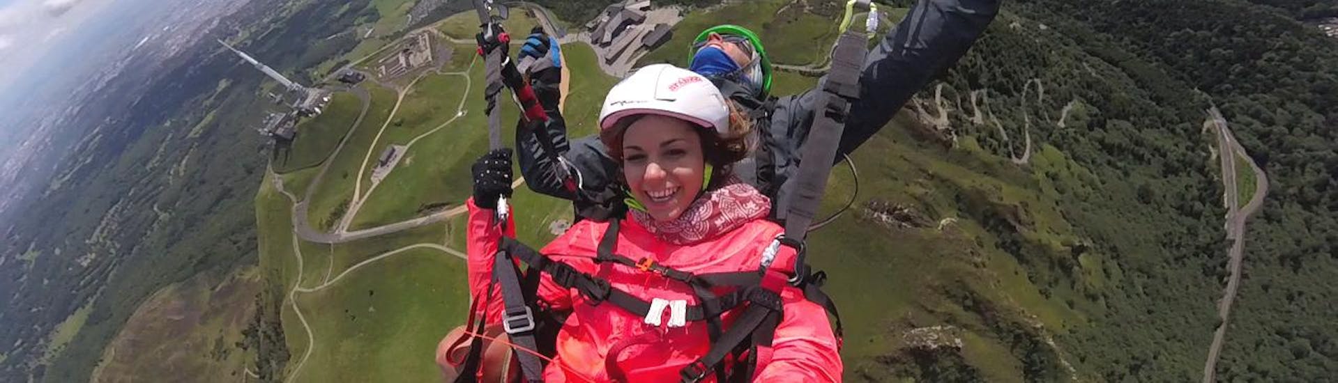 During the Tandem Paragliding "Sensations" - Puy de Dôme, an experienced paragliding pilot from Absolu Parapente is flying a woman who is thrilled with the spectacular views under her feet.
