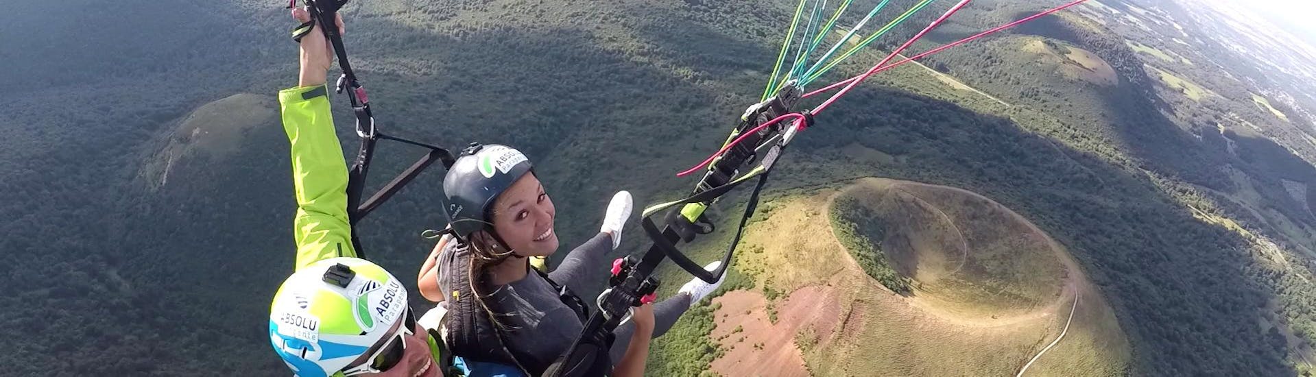 During the Tandem Paragliding "Performance" - Puy de Dôme, a woman is over the moon whilst flying safely over magnificent landscape with a qualified pilot from Absolu Parapente. 