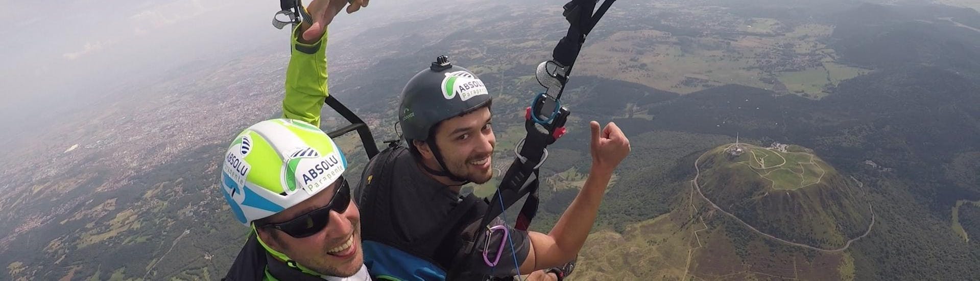 Un participant est ravi de voler avec son pilote de parapente d'Absolu Parapente au-dessus de paysages de volcans spectaculaires lors de son Vol Parapente Biplace "Découverte" - Puy de Dôme.