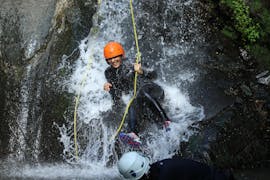 A woman is descending the watery rocks while doing her canyoning tour with ROCROI.