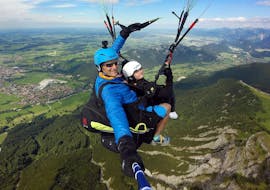 A tandem pilot from FlyTeam and his young passenger are soaring high above the Allgäu Prealps during the Tandem Paragliding "Panorama" from Breitenberg.