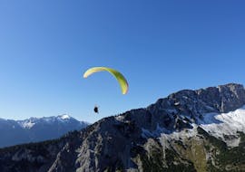 During the Tandem Paragliding "Long Distance Flight" in Allgäu and Tyrol, a paraglider from FlyTeam is soaring high above the mountains.