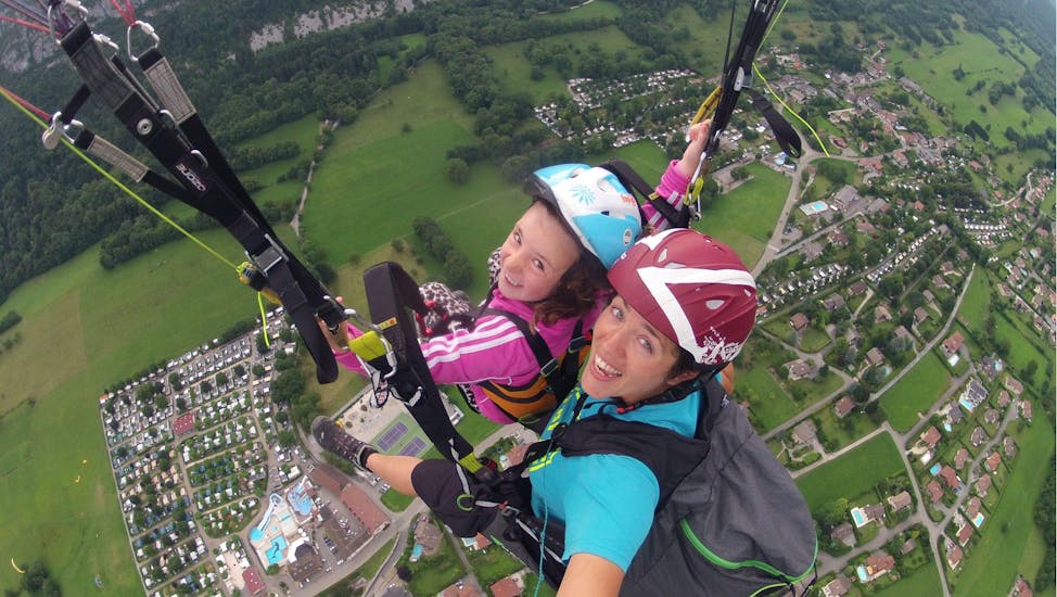A child is enjoying her Tandem Paragliding at Lake Annecy for Kids (3 -12 years) activity with FBI Parapente.
