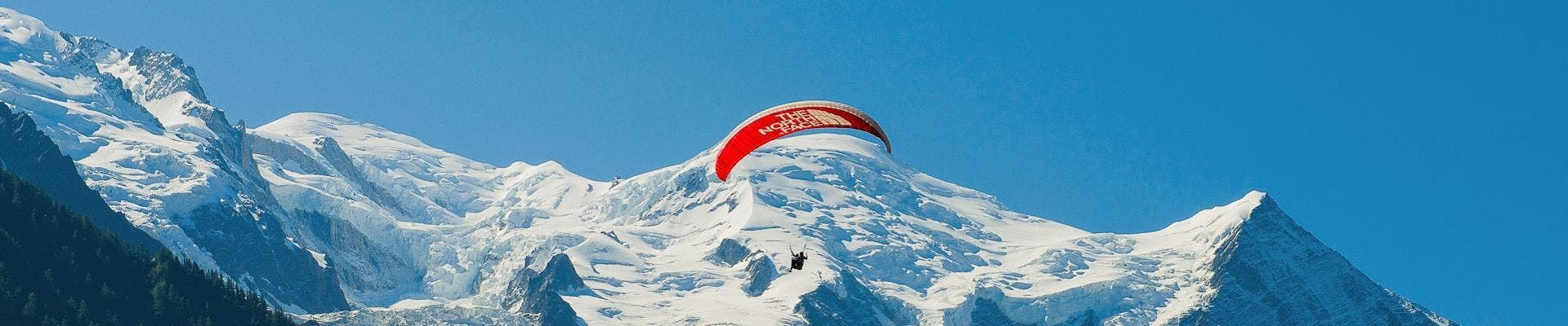 A paragliding pilot from Kailash Paragliding is flying above the mountains during a Tandem Paragliding Flight from Planpraz - Chamonix.